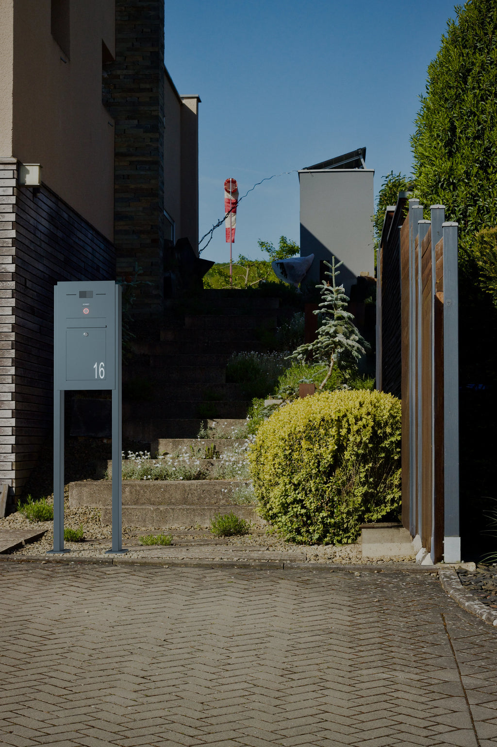 Freistehender Briefkasten Edelstahl B2 Audio LC mit Hausnummer 16 vor einer Treppe im Garten