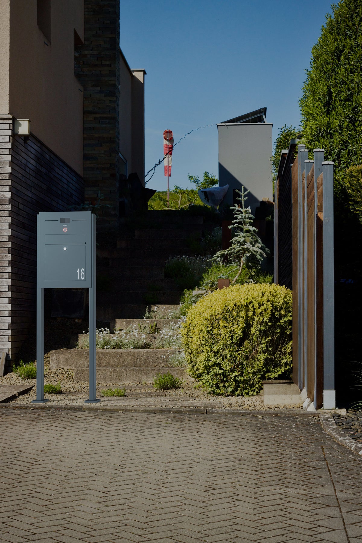 Freistehender Briefkasten Edelstahl B3A Audio LC mit Hausnummer 16 vor einer Treppe im Garten